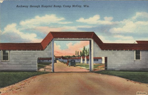 Colorized postcard view of an arch at Camp McCoy with ramps on either side and a road passing through it. Parked cars and barracks are on the far side of the arch. Caption reads: "Archway through Hospital Ramp, Camp McCory, Wis."