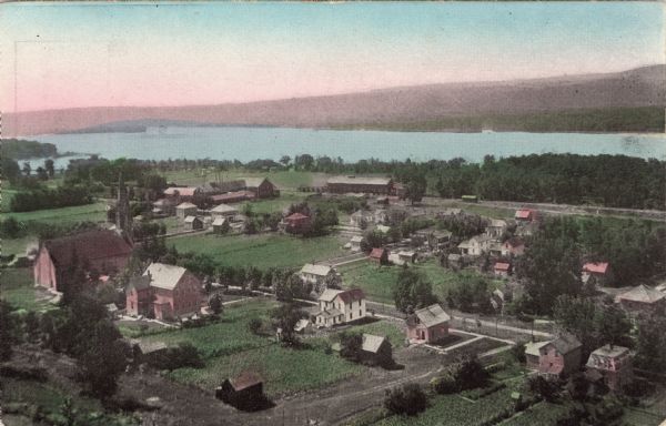 Colorized, elevated view of Cassville with the Mississippi River in the background. A church and dwellings are in the foreground.