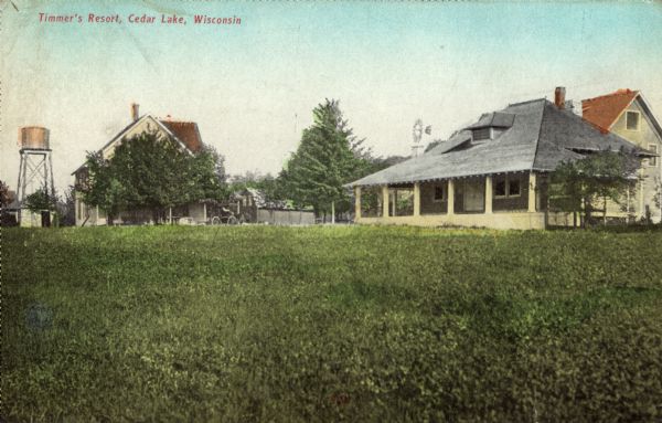 Hand-colored view across field towards Timmer's Resort, with a water tower and a windmill in the background. There is an automobile parked by a fence in the center.