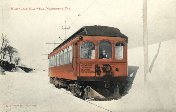 Hand-colored view of a Milwaukee Northern Interurban car on a snowy day. It stops at Milwaukee, Cedarburg, Grafton and Port Washington. The driver is sitting just inside the front window. Caption reads: "Milwaukee Northern Interurban Car."
