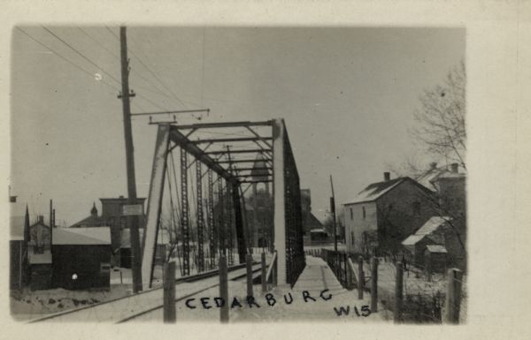 View towards Cedarburg through the railroad bridge. A pedestrian walkway is on the right, and City Hall is in the distance. Caption reads: "Cedarburg, Wis."
