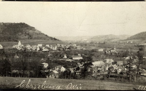 Elevated view of Chaseburg and the surrounding landscape, with a river and bluffs in the background. Caption reads: "Chaseburg, Wis."