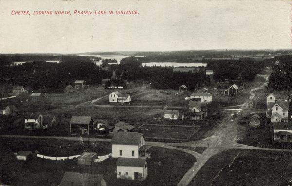 Elevated view of Chetek and Prairie Lake. There are dwellings on the edge of town. Caption reads: "Chetek, Looking North, Prairie Lake in Distance."