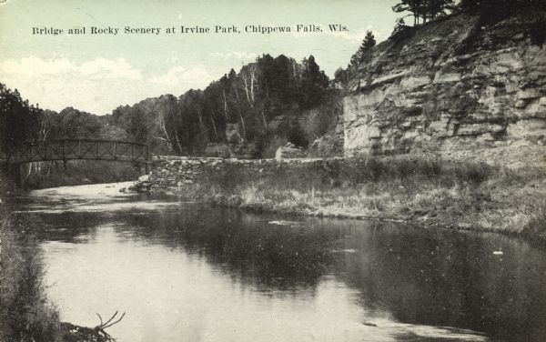 View of a bend in Duncan Creek with a bridge, trees, a quarried rock face and road in Irvine Park (probably the "Bear Cage Road"). Caption reads: "Bridge and Rocky Scenery at Irvine Park, Chippewa Falls, Wis."
