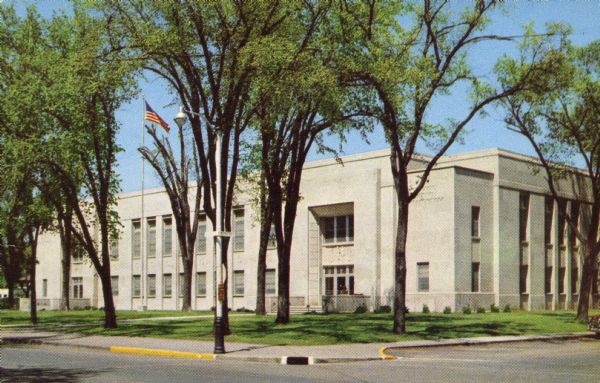 Color postcard of new County Court House, a two-story white granite building with elm trees in front.