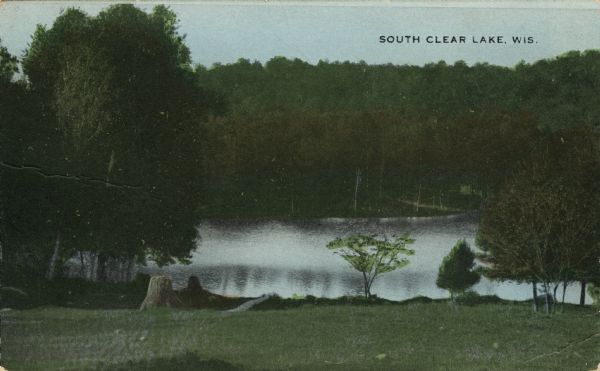 Colorized postcard view down hill toward the lake. Caption reads: "South Clear Lake, Wis."