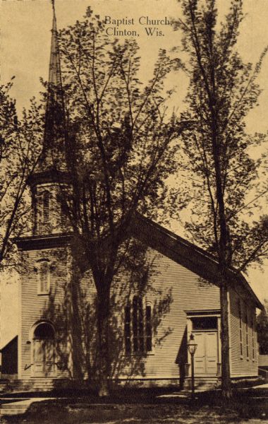 View of the Baptist Church, obscured by trees. Caption reads: "Clinton Baptist Church, Clinton, Wis."