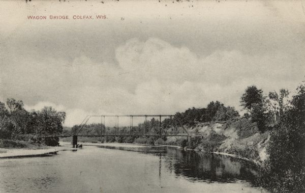 Black and white photographic postcard looking up river towards the Wagon Bridge. Caption reads: "Wagon Bridge, Colfax, Wis."