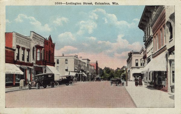Color photograph of Ludington Street, with parked automobiles and pedestrians and the post office on the left. Caption reads: "Ludington Street, Columbus, Wis."
