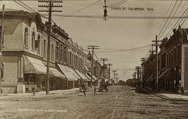 Photographic postcard of James Street, looking east, with pedestrians and horse-drawn vehicles. Caption reads: "James St. Columbus Wis."