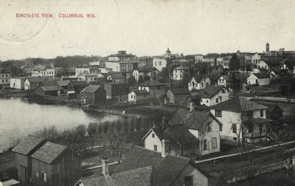 Photographic postcard of an elevated view looking across the downtown area. The Crawfish River is on the left. Caption reads: "Bird's-Eye View, Columbus, Wis."