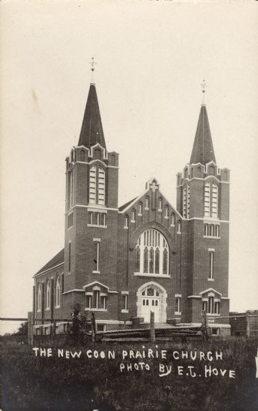 View toward the front of the church, a brick building with two spires. Caption reads: "The New Coon Prairie Church."