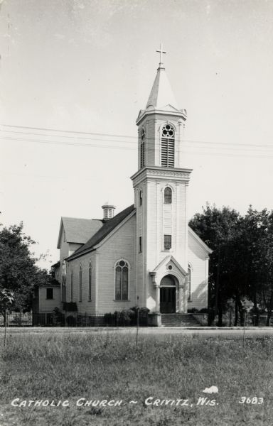 Photographic postcard view from across the road towards the church. Caption reads: "Catholic Church — Crivitz, Wis."