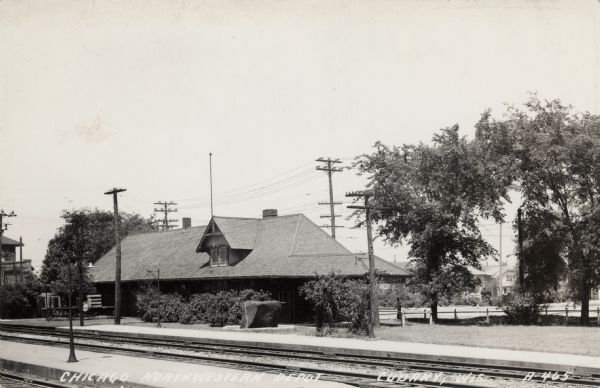 Photographic postcard view across railroad tracks towards the depot. Caption reads: "Chicago Northwestern Depot, Cudahy, Wis."