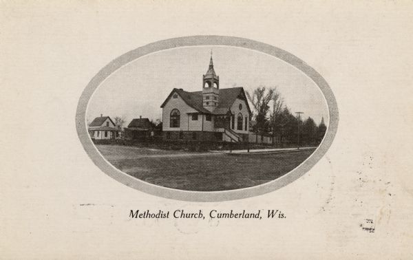 Oval-framed view from unpaved street towards the Methodist Church, shown in an oval frame in the center of a white postcard. There are two houses in the background on the left. Caption reads: "Methodist Church, Cumberland, Wis.: