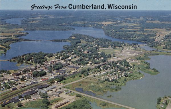 Aerial view of the Island City surrounded by the waters of Beaver Dam Lake, and by a vacation and recreation area that includes some fifty lakes within a radius of ten miles. Caption reads: "Greetings from Cumberland, Wisconsin."