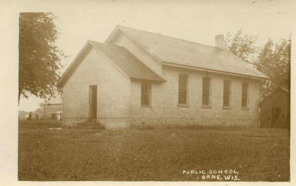 Photographic postcard view of the brick public school building. Caption reads: "Public School, Dane, Wis."