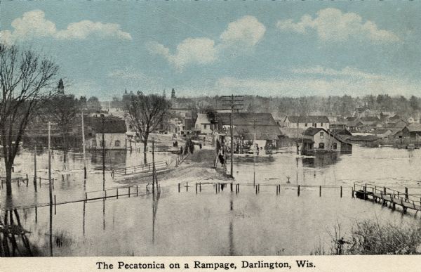 Elevated view of the Pecatonica River at the bridge. The river is flooding the town. Caption reads: "Pecatonica River on a Rampage, Darlington, , Wis."