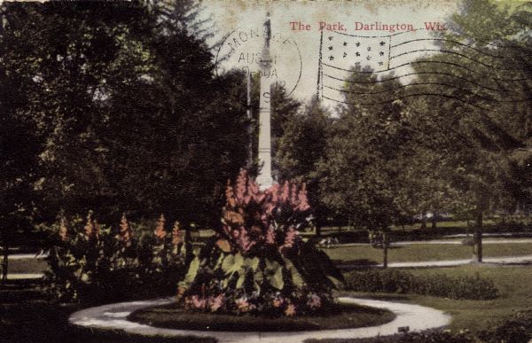 View of the park, with plantings and the Soldier's Monument. Caption reads: "The Park, Darlington, Wis."