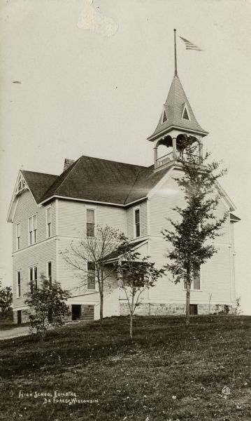 View across lawn towards the high school building, with a bell tower. Caption reads: "High School Building, De Forest, Wis."