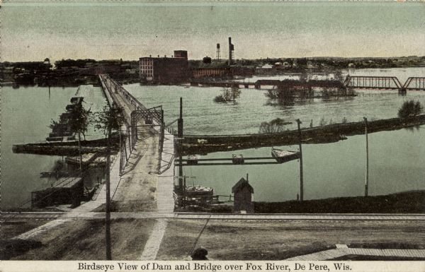 Color-enhanced postcard with an elevated view of the dam and swing bridge over the lock on the Fox River. Caption reads: "Birdseye View of Dam and Bridge over Fox River, De Pere, Wis."