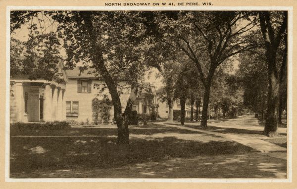 View of residential area, with houses, road, trees and sidewalks. Caption reads: "North Broadway on W 41, De Pere, Wis."