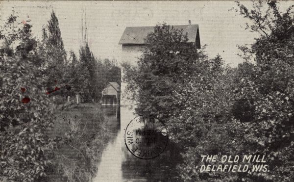 Black and white photographic postcard view of an old mill and stream. Caption reads: "The Old Mill at Delafield, Wis."