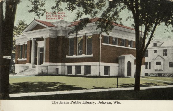 Hand-colored view from street of the public library building on Fourth Street. Caption reads: "The Aram Public Library, Delavan, Wis."