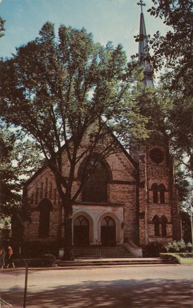 View from across street of the front of St. Andrews Church. There are wide steps and a central railing leading up to the entrance. The steeple of the church is on the right.