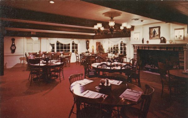 Interior view of the dining room at Millie's Pancake Haus. The tables are set, and there is a large fireplace on the back wall on the right.

Text on reverse reads: "Millie's Pancake Haus Complete Menu Featuring Pennsylvania Dutch Type Dinners and Pancake Specialties Interesting Shops; County O and South Shore Drive, Delavan Wis., Phone 414-728-2434 Closed Monday."