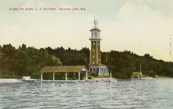Color postcard view across water towards L.P. Sutter's tower along the shore of Delavan Lake. Caption reads: "Along the Shore, L.P. Sutter's, Delavan Lake, Wis."