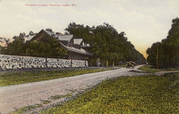 View down side of road towards Penwern Lodge on the other side of the road. There is a stone wall in front of the lodge, and a horse-drawn wagon near the entrance. Caption reads: "Penwern Lodge, Delavan Lake, Wis."