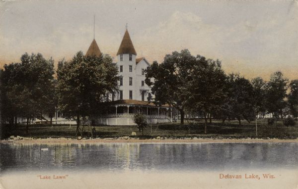 View across water towards the Lake Lawn Resort on Delavan Lake. The hotel is a large white building with a wrap-around porch, and two spires. Caption reads: "'Lake Lawn,' Delavan Lake, Wis."