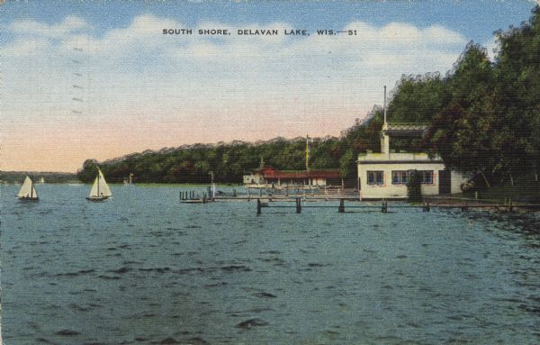 View across water towards boathouses and piers along the shoreline at Delavan Lake. There are sailboats in the lake. Caption reads: "South Shore, Delavan Lake, Wis."