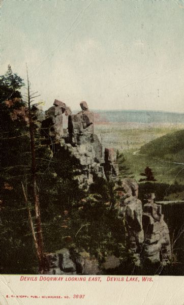Colorized elevated view of the Devil's Doorway rock formation. Caption reads: "Devils [sic] Doorway, Looking East, Devils [sic] Lake, Wis."