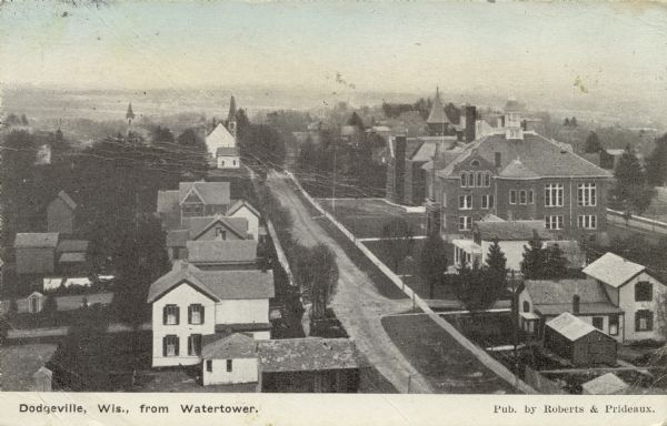 Elevated view of Dodgeville from the village water tower, showing houses, church steeples, sidewalks, and unpaved road. Caption reads: "Dodgeville, Wis., from Watertower."