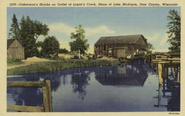 Color enhanced postcard view of fisherman's shacks on the outlet of Logan's creek on the shore of Lake Michigan.