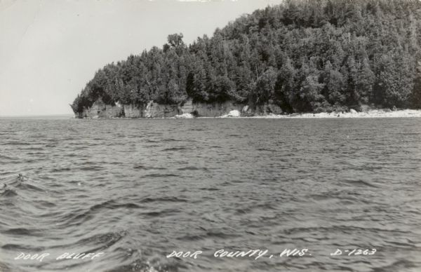Black and white photographic postcard view across water towards Door Bluff on the shore of Lake Michigan.