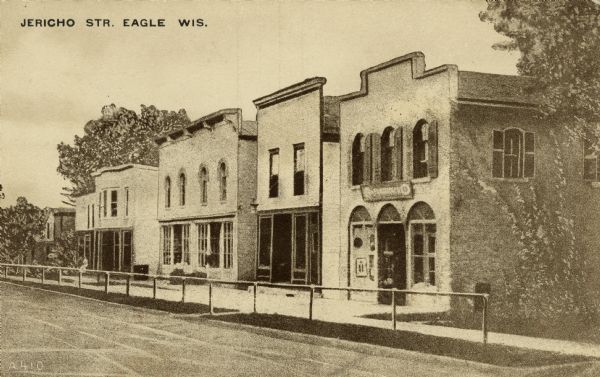 Artist's rendering of Jericho Street, showing storefronts. There is a metal railing between the sidewalk and the street. Caption reads: "Jericho Str. Eagle, Wis."