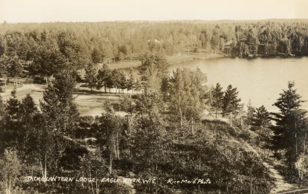 Aerial photographic postcard of Jack O'Lantern Lodge on Taylor Lake east of Eagle River on STH70, including the forest area surrounding the shoreline. Caption reads: "Jack O'Lantern Lodge, Eagle River, Wis."