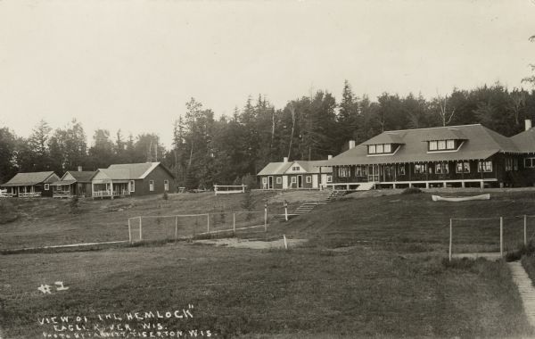 View across lawn towards main lodge and cabins at the Hemlock Resort on the east shore of Catfish Lake, STH 70, east of Eagle River. Caption reads: "View of 'The Hemlock' Eagle River, Wis."