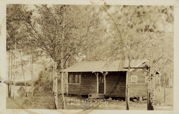 View toward a cabin among birch trees at the resort adjacent to the lake, on STH 17 south of Eagle River. Caption reads: "Indian Lake Resort, Eagle River, Wis."