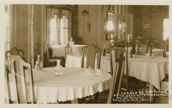 View of the dining room. The resort is on Pickerel Lake, east of STH 55 at 580 Flint Ridge Lane and south of Crandon. Caption reads: "Corner of Dining Room at Halberstadt's Pickerel Point Resort. Eagle River, Wis."