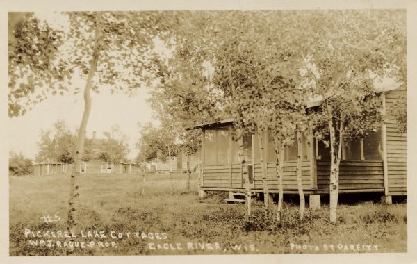 View toward a cottage at the resort, northwest of Eagle River on CTH G. Other cabins are in the background on the left. Caption reads: "Pickerel Lake Cottages, Wm J. Radue — prop. Eagle Lake, Wis."