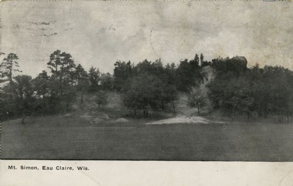 View across field towards the back of Mt. Simon. Caption reads: "Mt. Simon, Eau Claire, Wis."