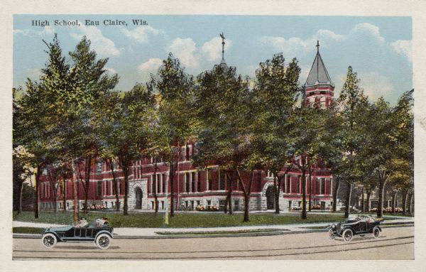 Hand-colored view of the high school with arched stone entrances. There are trees on the lawn and flowers near the foundation of the building. People are riding in open automobiles along the street in front. Caption reads: "High School, Eau Claire, Wis."