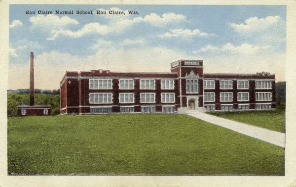 View of the Eau Claire Normal School, with a lawn in front, and a small coordinated building to the left with a large smokestack or tower.