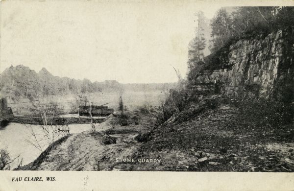 Black and white photographic postcard of a stone quarry. Caption reads: "Eau Claire, Wis." and "Stone Quarry."