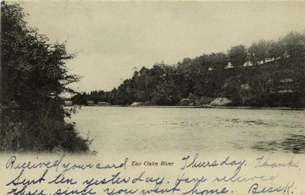 Black and white photographic postcard view of the Eau Claire River and shoreline. Caption reads: "Eau Claire River."