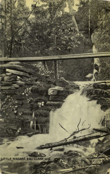 Black and white photographic postcard view of a waterfall on the Little Niagara River. A footbridge extends over the waterfall.
